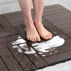 A person standing on a brown interlocking anti-slip plastic mat with soapy water splashes.