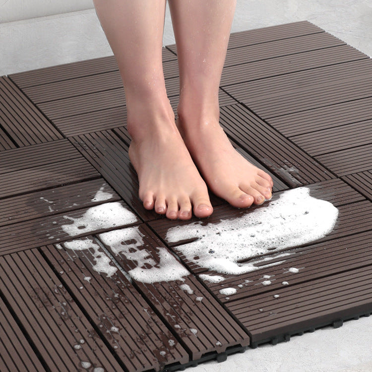 A person standing on a brown interlocking anti-slip plastic mat with soapy water splashes.