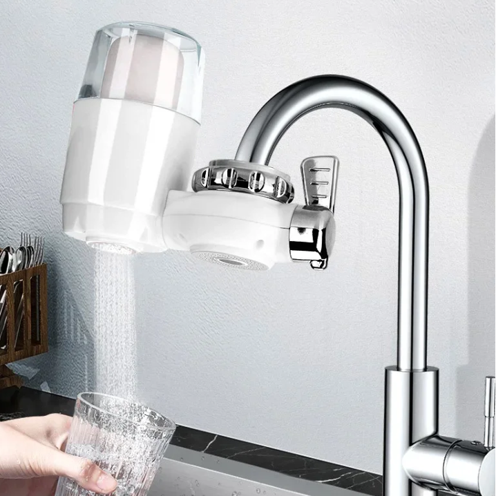 Kitchen faucet with a water filter attachment and a glass being filled with water.